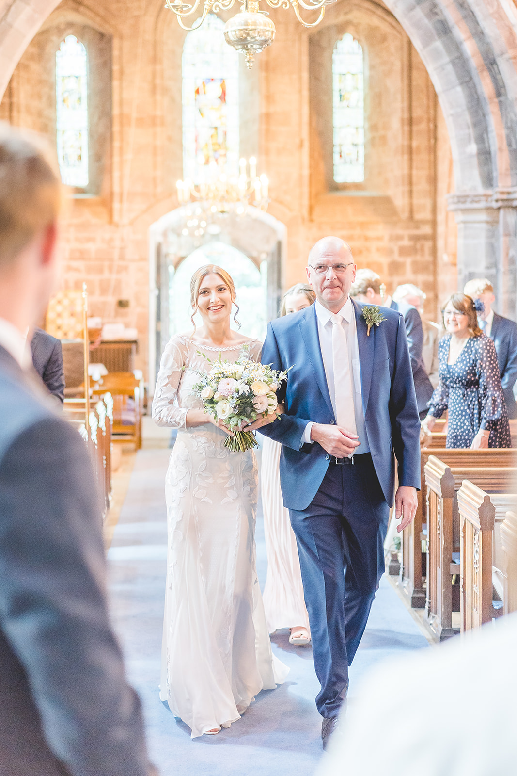 bride and father walk up church aisle in wedding photograph 