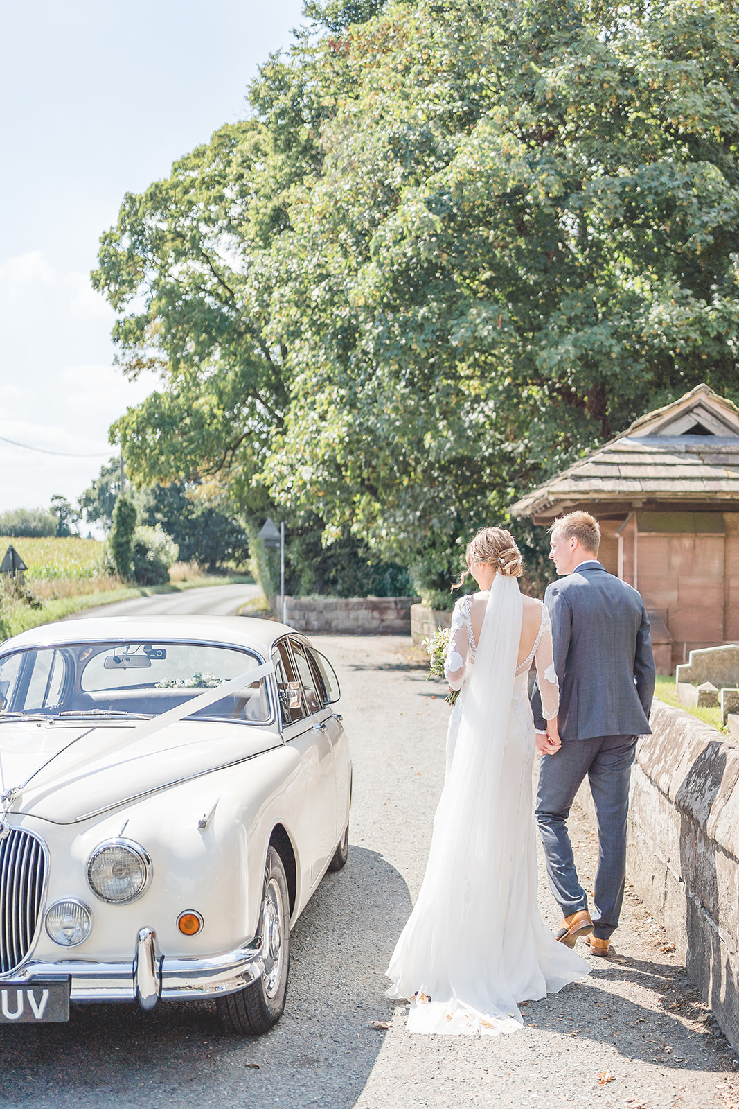 bride and groom walk to classic wedding car 