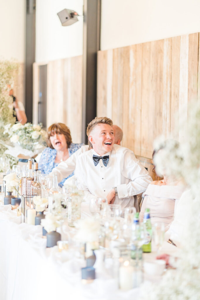 groom laughs during speeches at foxtail barns 