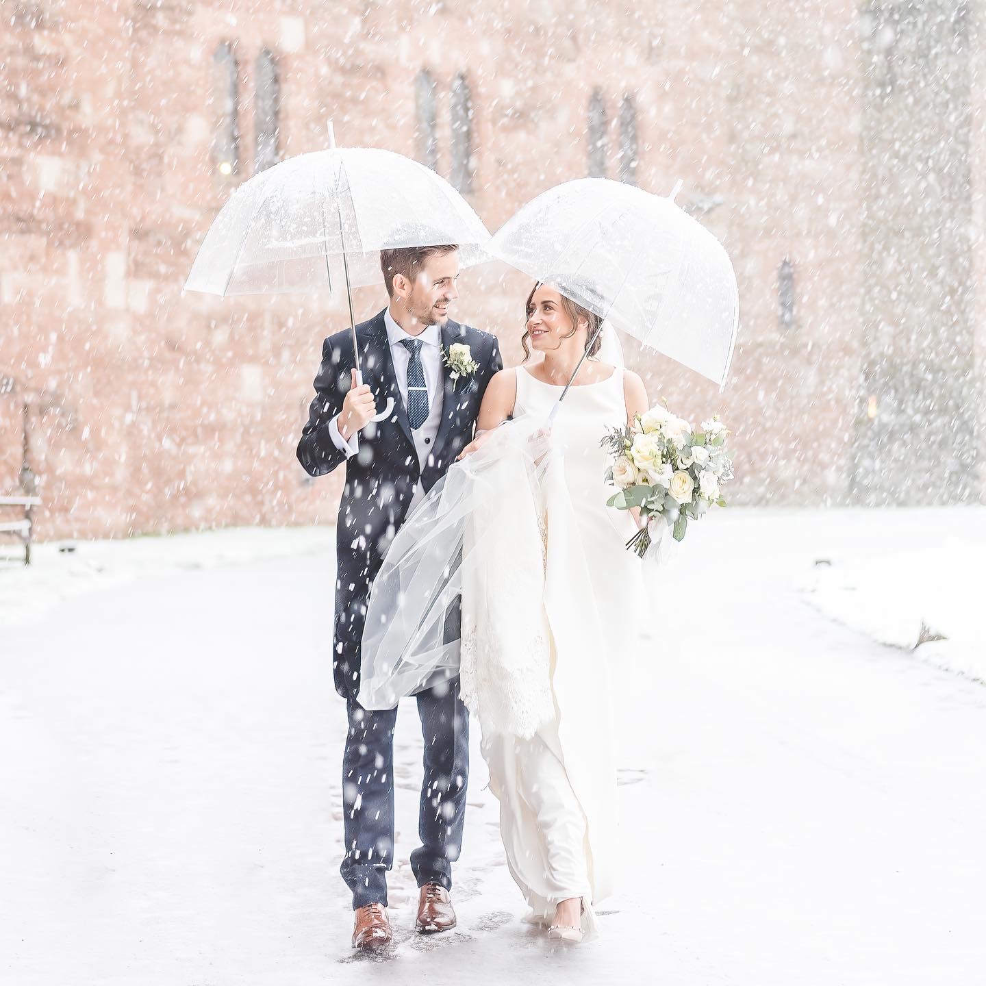 bride and groom walk through snow at peckforton castle 