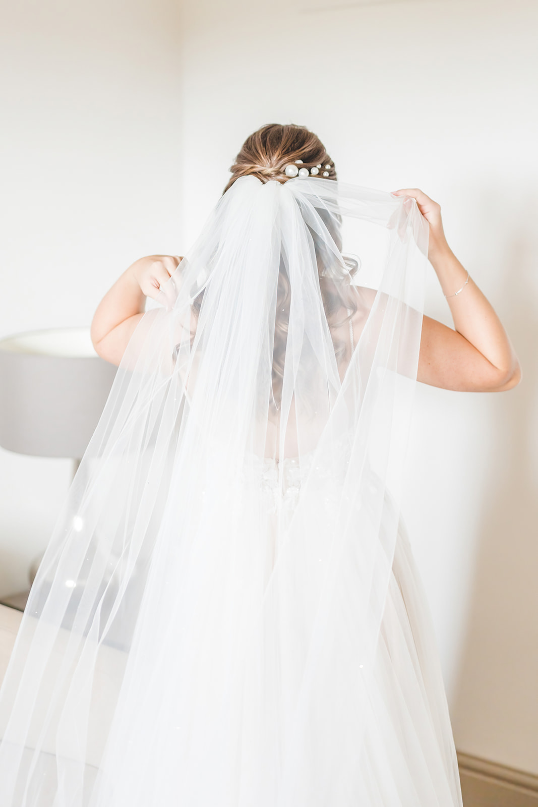 bride with pearls in hair adjusts veil 