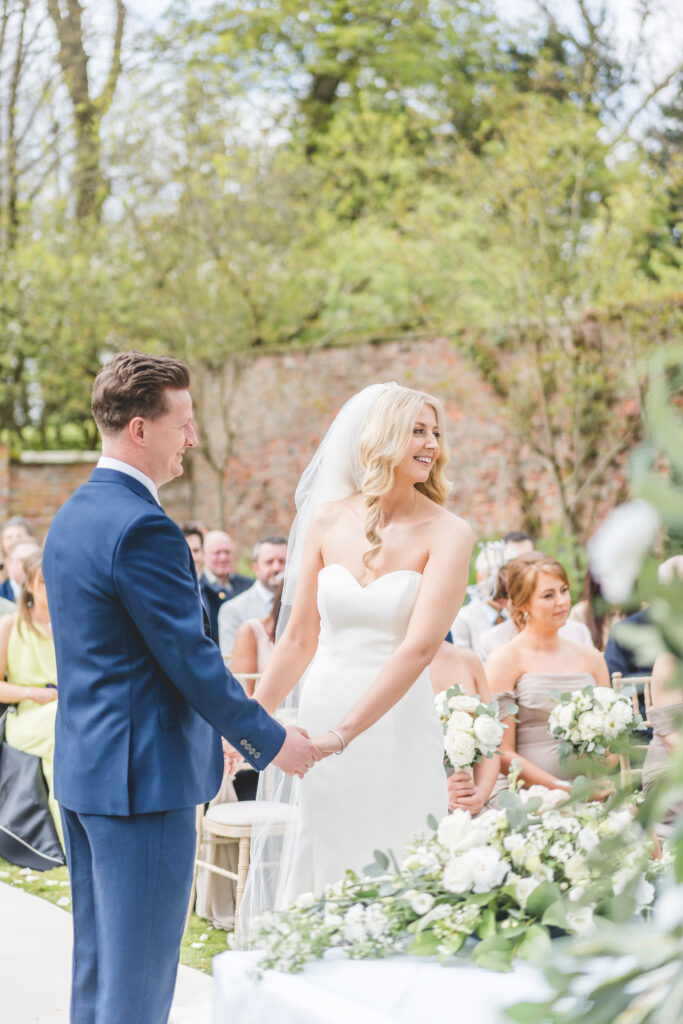 bride and groom hold hands during outdoor ceremony at Saltmarshe Hall Wedding