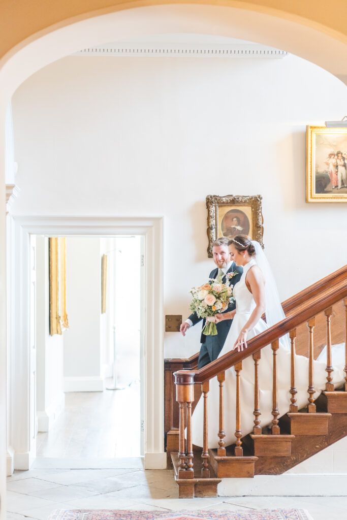 bride and father walk down stairs at at iscoyd park wedding venue