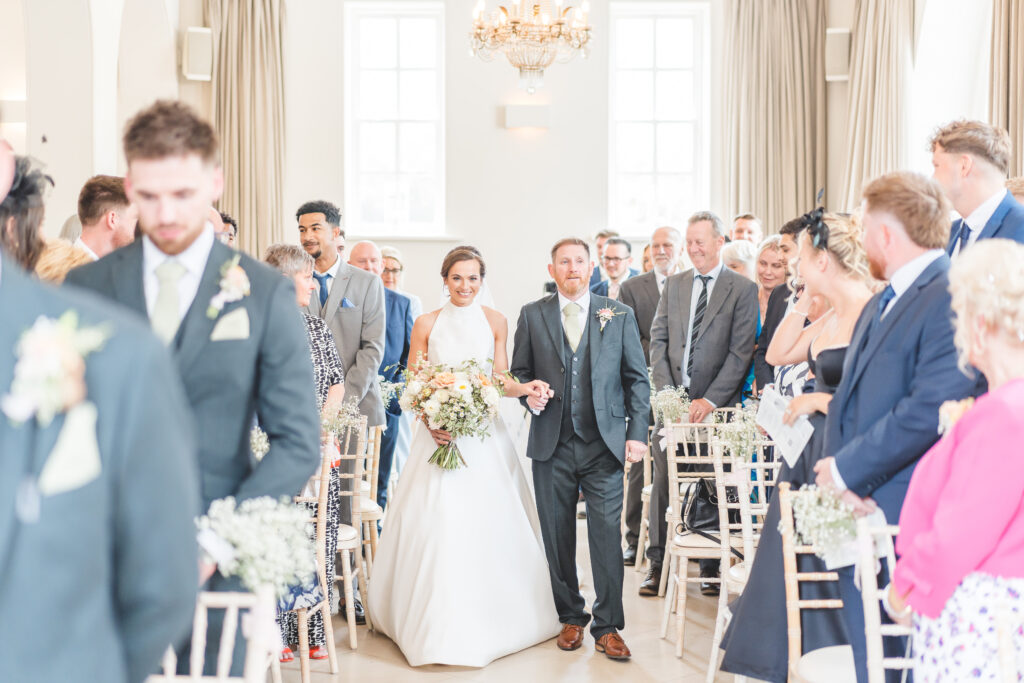 bride and dad walk down the aisle together at iscoyd park wedding venue