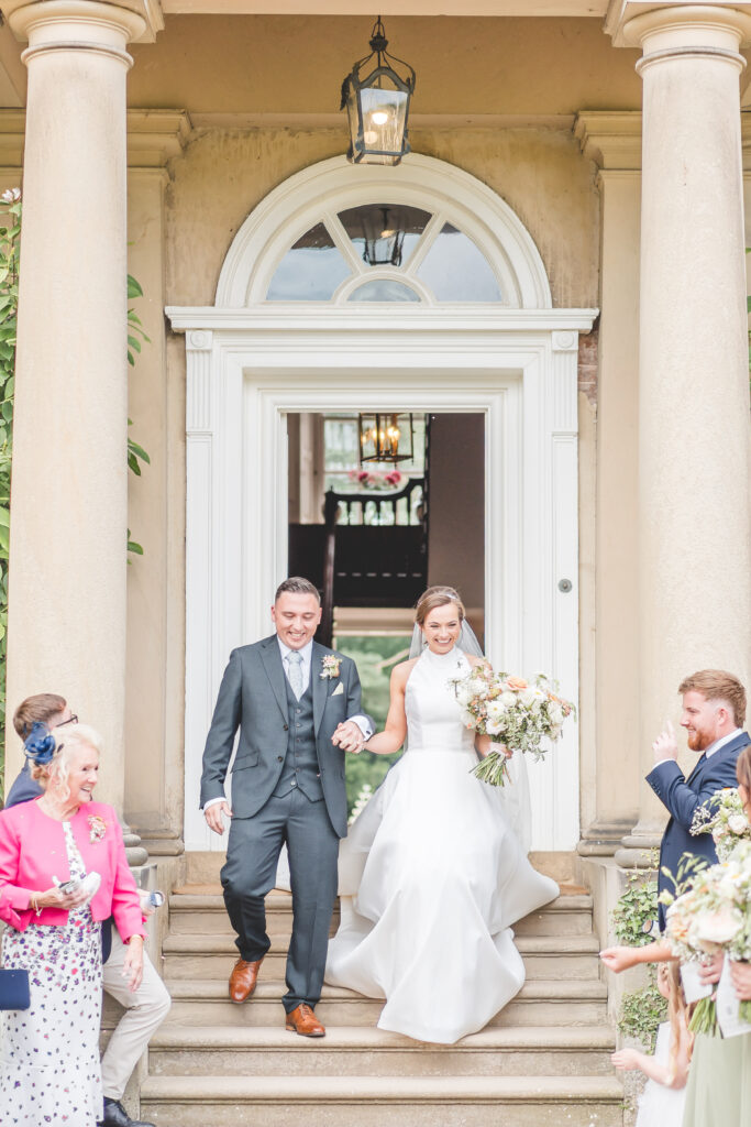 bride and groom are greeted by guests leaving the main entrance at iscoyd park wedding venue in Shropshire