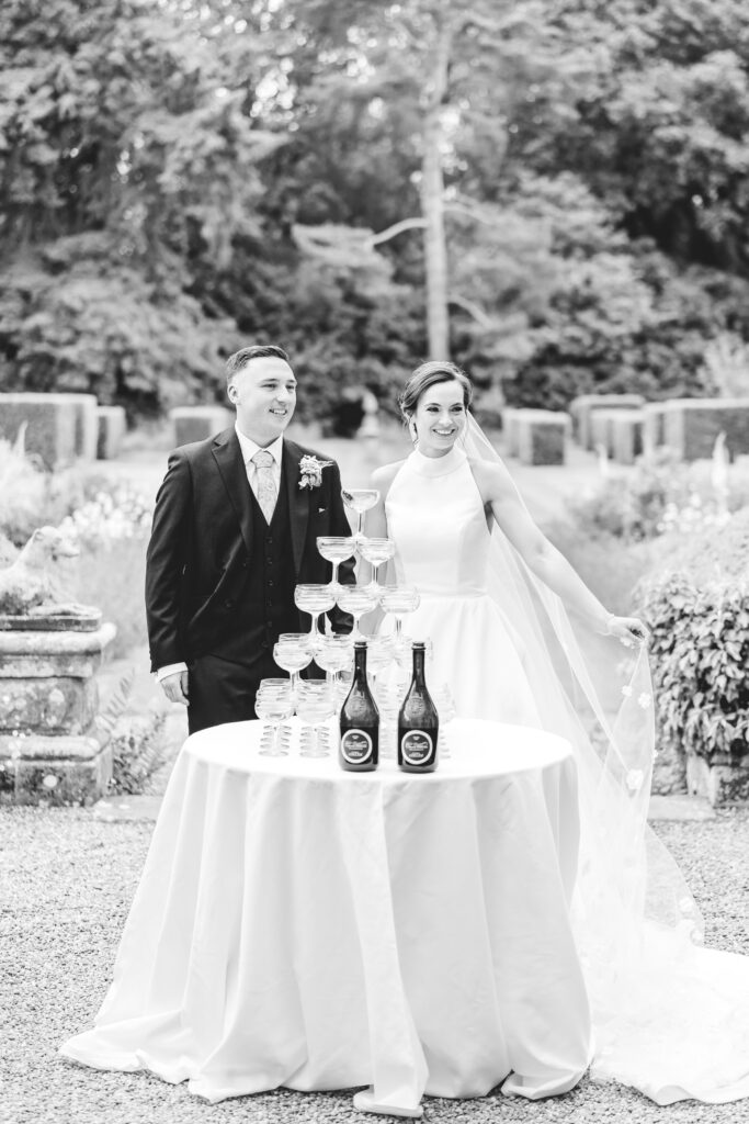 bride and groom prepare to do a champagne tower at iscoyd park wedding venue in Shropshire
