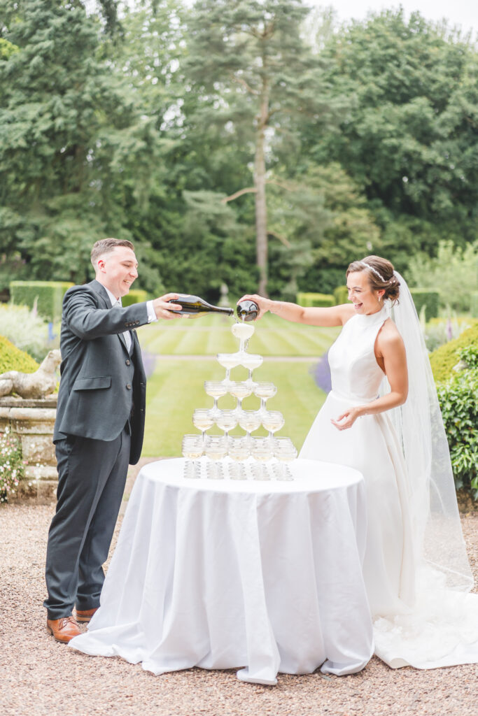 bride and groom pour champagne tower at iscoyd park wedding venue in Shropshire