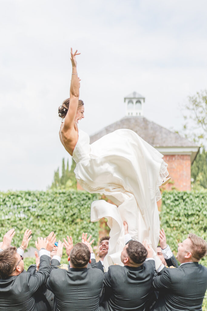 bride is thrown in the air by the groomsmen at iscoyd park wedding venue in Shropshire