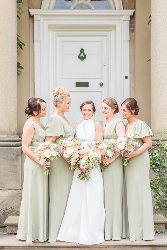 bridesmaid portraits in sage green dresses with peach florals at iscoyd park wedding venue in Shropshire