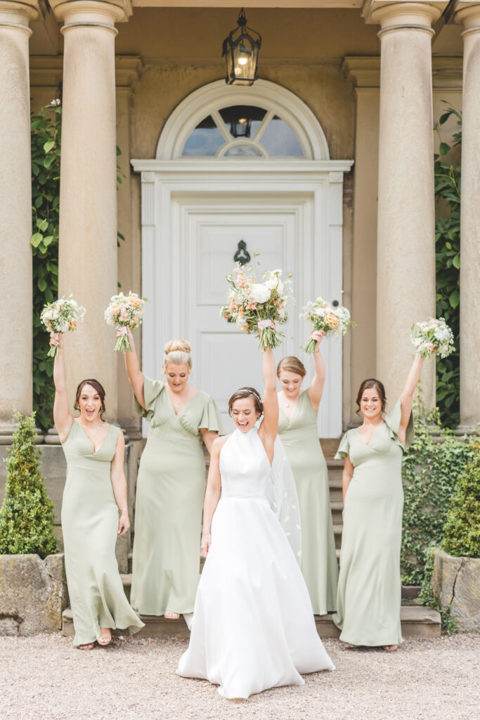 bridesmaid dance in sage green dresses with peach florals at iscoyd park wedding venue in Shropshire