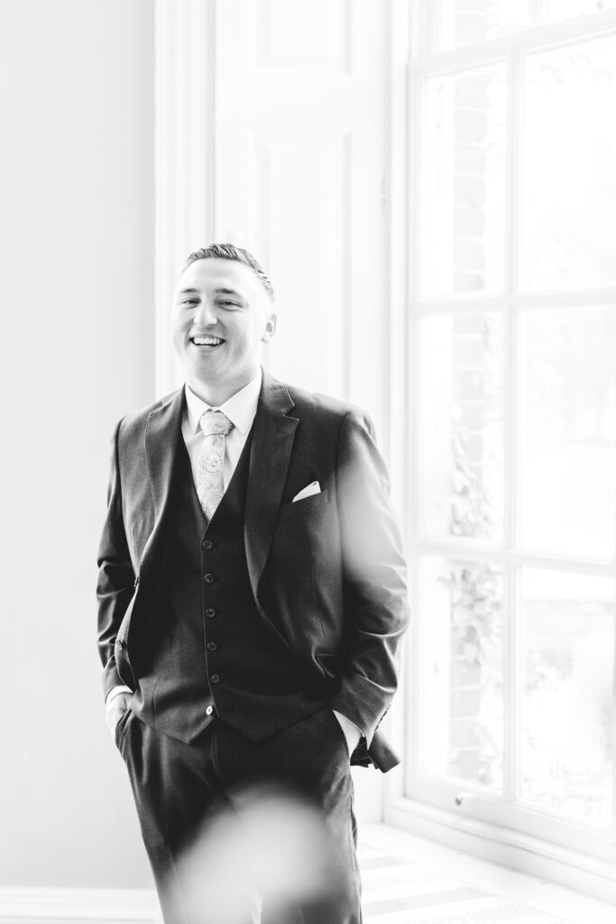 groom laughs in the window at iscoyd park