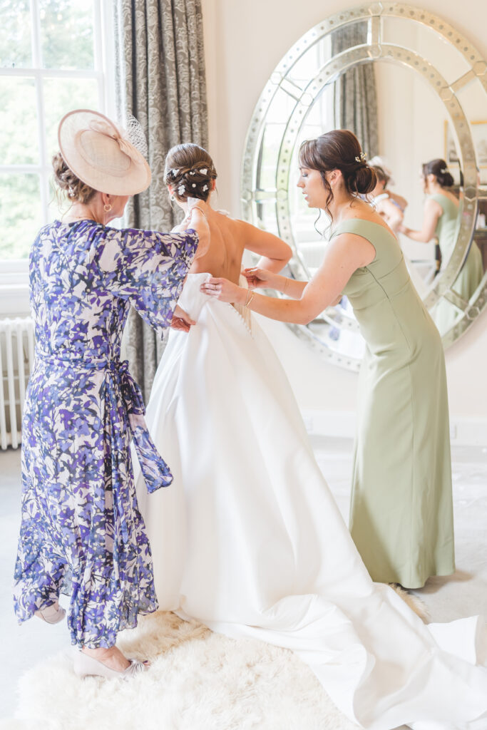 bride gets into dress in the bridal suite at iscoyd park